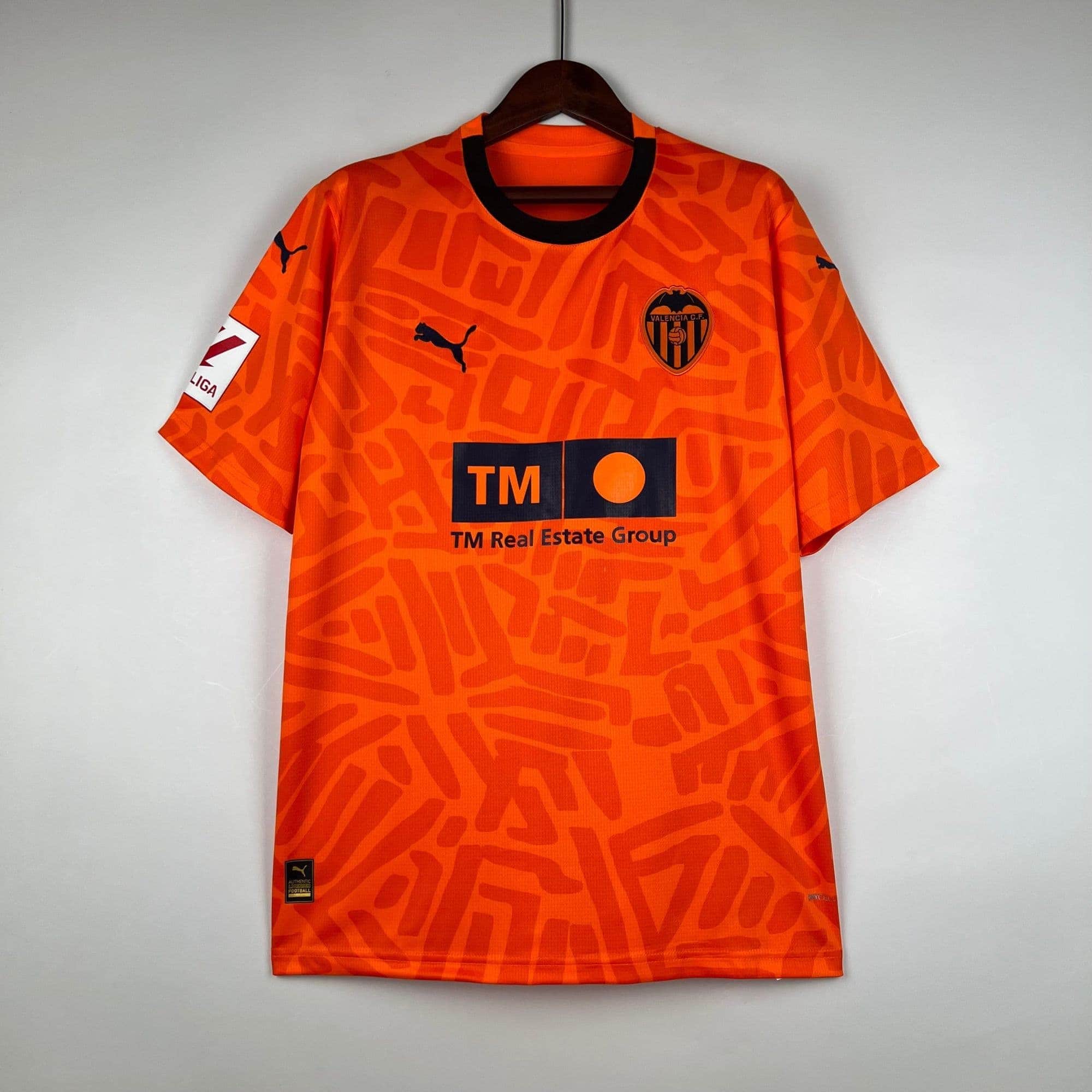 00922db8_8c797a48-6d69-4e83-9051-449ce29c2056 | AE JERSEY Orange Valencia CF football jersey on a hanger, featuring a black collar and a team crest on the chest left side.