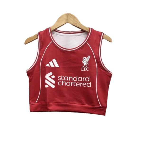 Red cropped sleeveless football jersey with white piping, Liverpool FC crest, Adidas logo, and 'Standard Chartered' sponsor on a hanger