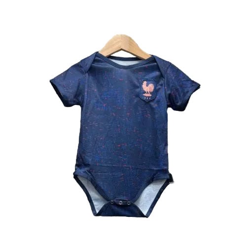 Navy blue baby onesie with pink speckles hanging on a wooden hanger, featuring a rooster emblem on the left chest.