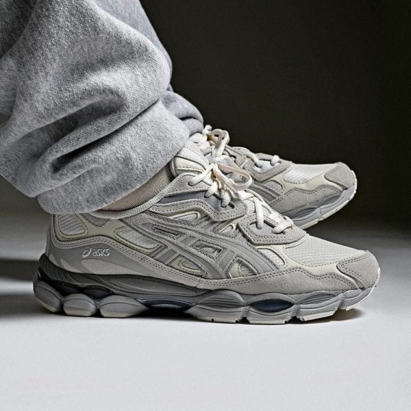 Gray Asics running sneakers with a chunky sole, worn with light gray sweatpants/leggings.