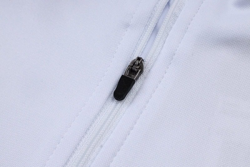 0c9dfb81 | AE JERSEY Close-up of a white fabric garment zipper with a black zipper pull along a seam.