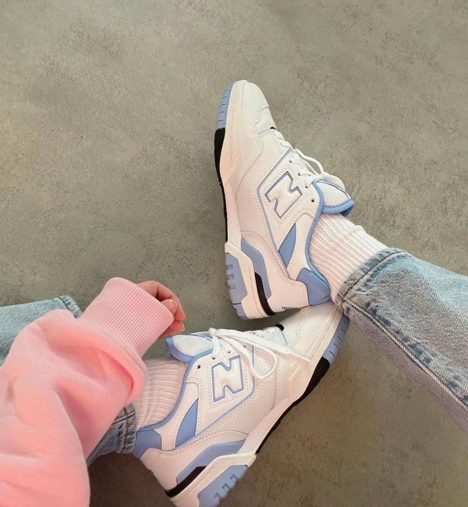 0ecab0cc-738d-4a90-9b0b-04435a42e3f7_e12e4d58-fadd-4e09-ad34-3374475be390 | AE JERSEY White and light-blue sneakers worn with light-wash jeans on a gray floor, pink sleeve peeking from the left.