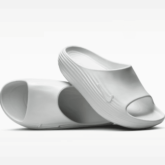 Pair of white open-toe slides with a textured strap and a Nike swoosh on the side.