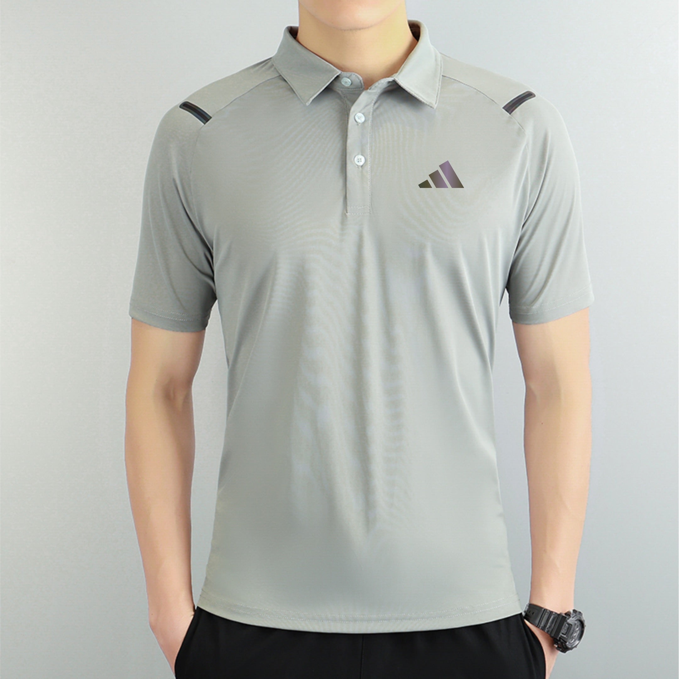 130f5ef4 | AE JERSEY Person wearing a light gray polo shirt with a small purple gradient logo on the left chest, and a black watch on the right wrist.