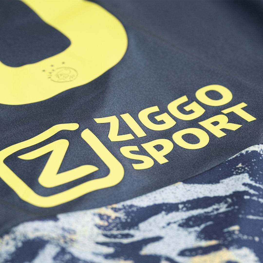 14zU4BqMlTXgknB | AE JERSEY Close-up of bright yellow Ziggo Sport logo on dark fabric (branding on apparel).