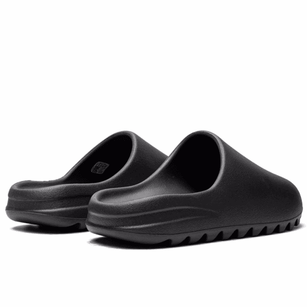 Black slide sandals with thick cushioned sole, open-toe design, shown from a side angle.