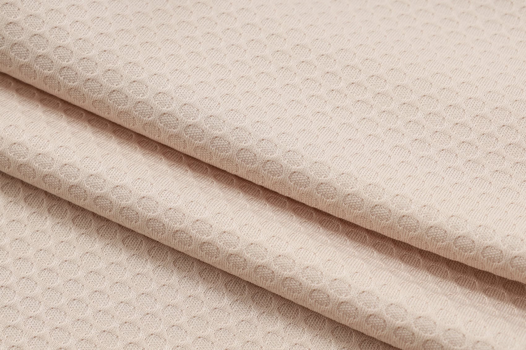 1e50d3b3 | AE JERSEY Beige fabric folded with a small, repeating dotted texture pattern.