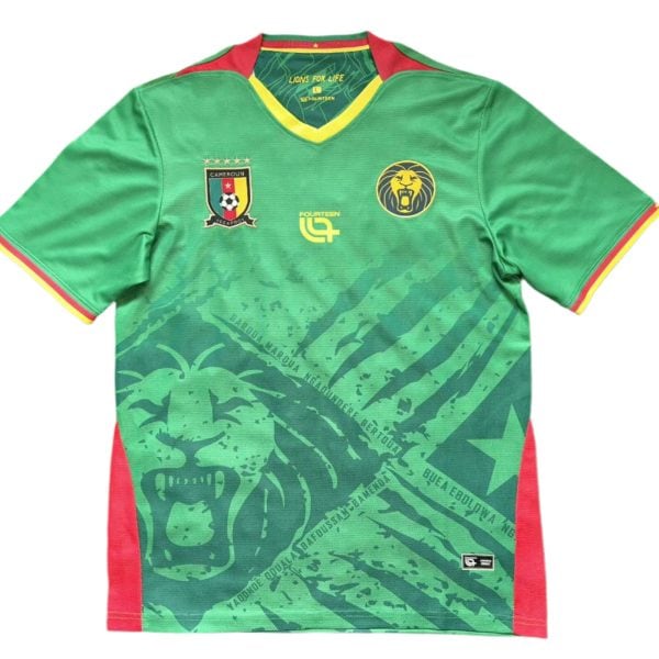 Green Cameroon national football jersey with red/yellow trim and crest on the left chest, lion emblem on the right.