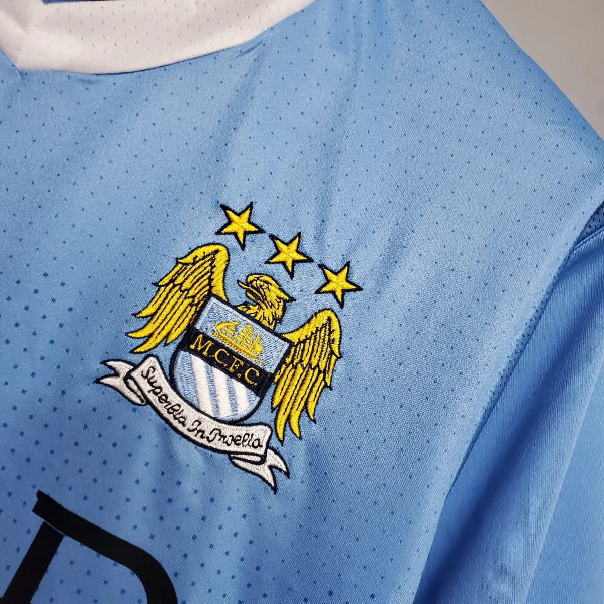 2012-Manchester-City-Retro-Home-Short-Sleeve-Jersey3 | AE JERSEY Manchester City crest on a light blue perforated jersey, featuring a gold eagle and the motto banner 'Superbia in Proelio'