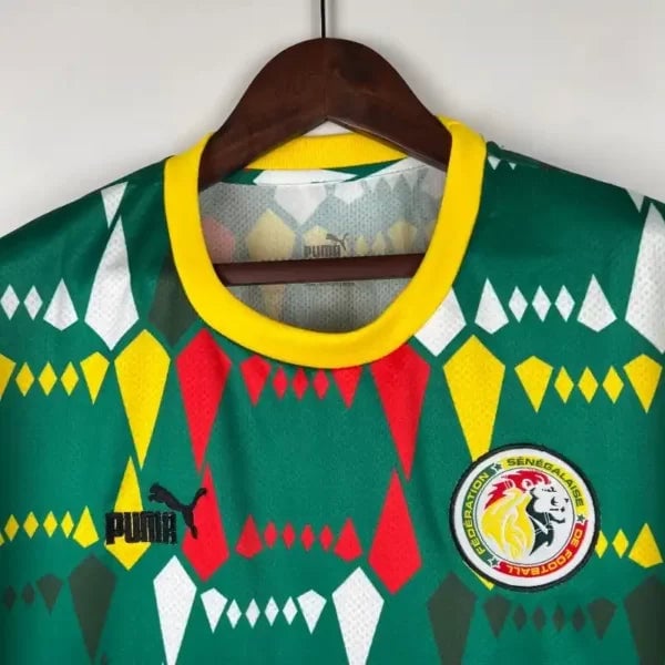 2023-Senegal-Soccer-Jersey-Home-1-600x600-1 | AE JERSEY Green football jersey on hanger with a yellow collar, featuring a geometric red, yellow, and white diamond pattern, Puma logo, and federation badge on the chest.