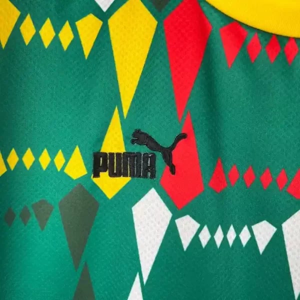 2023-Senegal-Soccer-Jersey-Home-6-600x600-1 | AE JERSEY Close-up of green fabric with geometric diamond shapes in yellow, red, and white, featuring the black PUMA logo (wordmark with jumping cat).