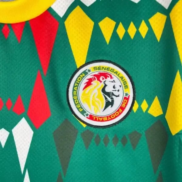 2023-Senegal-Soccer-Jersey-Home-8-600x600-1 | AE JERSEY Close-up of a green soccer jersey with red, yellow, and gray geometric shapes and the Senegal Football Federation crest in the center.