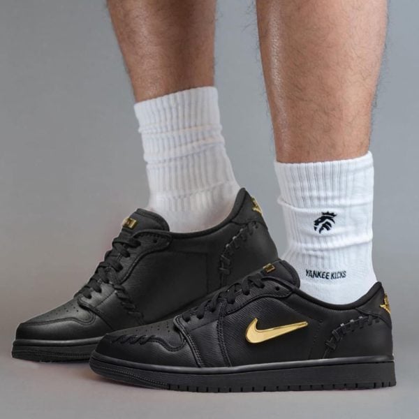 Lower legs in white ribbed crew socks with black sneakers featuring a gold Nike swoosh