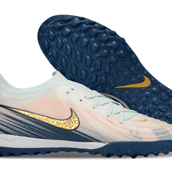 Nike turf soccer shoe with pale pink upper, mint laces, and dark blue outsole featuring a gold swoosh.