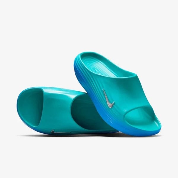 Turquoise slip-on sandals with a white Nike swoosh, gradient blue sole, shown on a white background.
