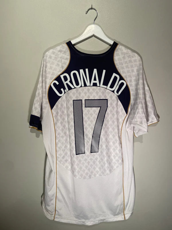 3F3BC23A-63F6-47BB-B565-13EE1F273FB6 | AE JERSEY Back view of a white soccer jersey on a hanger, navy curved panel with gold trim reads 'CRONALDO' and the number 17