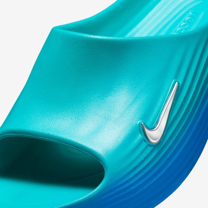 40afa725_0a54_4963_9562_f0451d39c906 | AE JERSEY Close-up of a turquoise Nike slide with a silver swoosh and ribbed sole.