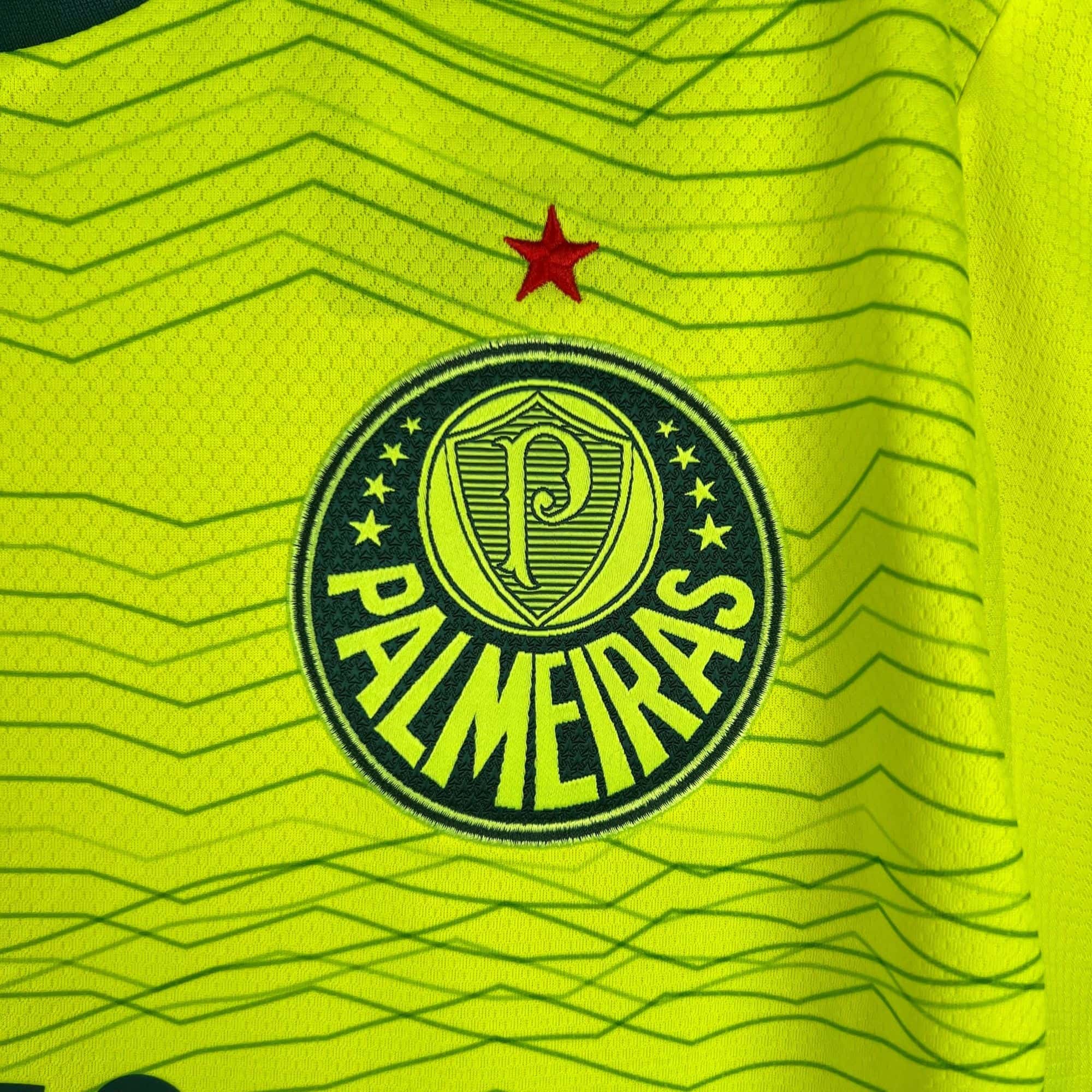 40cf0416_270e9e92-8e65-437a-88d5-6dd1e45b63c1 | AE JERSEY Close-up of neon yellow high-visibility fabric with a red star and a circular emblem nearby.