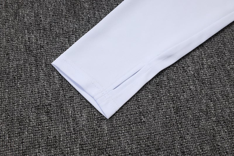 4367f44c | AE JERSEY White shirt sleeve cuff extended on a dark gray carpet.
