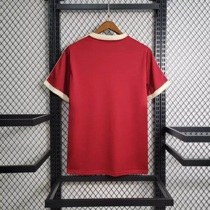 47e99783235d86fc_6b6ca833-1e02-4147-9d7e-d6f705e2f654 | AE JERSEY Red short-sleeve sports jersey hanging on a wooden hanger against a metal rack, back view with cream collar and cuffs.