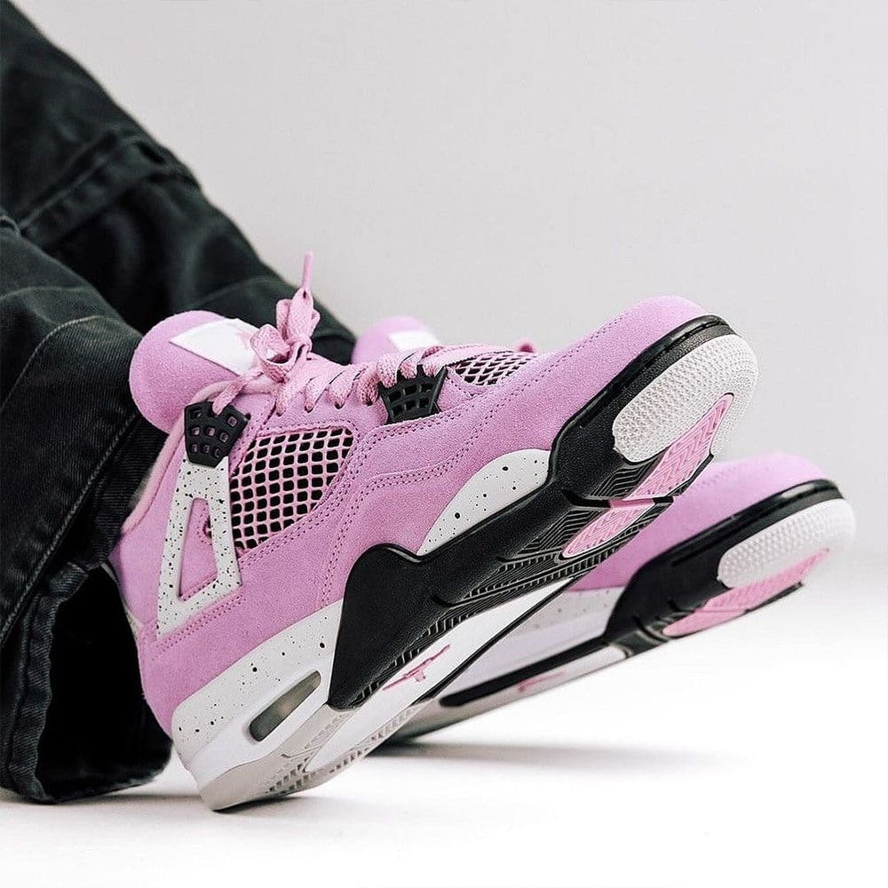 484116871_618673307738645_8619288751989252428_n | AE JERSEY Pink athletic sneakers with white and black sole resting on their side, denim-black pants visible in the background.