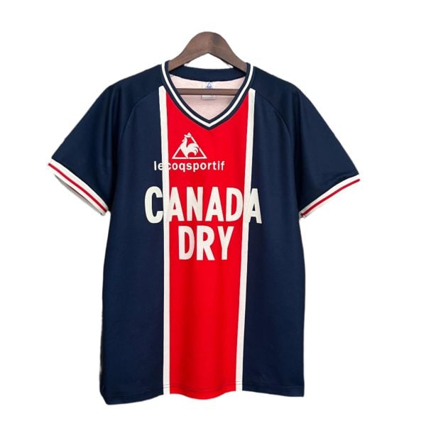 Navy blue Le Coq Sportif Canada Dry sports jersey on a wooden hanger with a red center panel and white trim, displaying the brand logo.