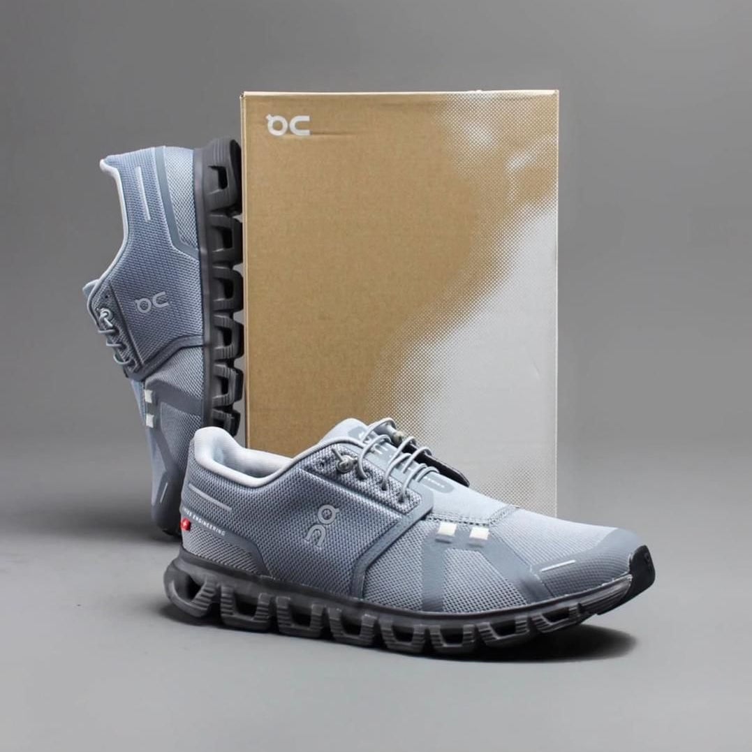 48b98190-6af2-4d3f-aecb-1eab1ee86184 | AE JERSEY Light gray running shoes with a chunky black sole, positioned in front of a brown shoebox.