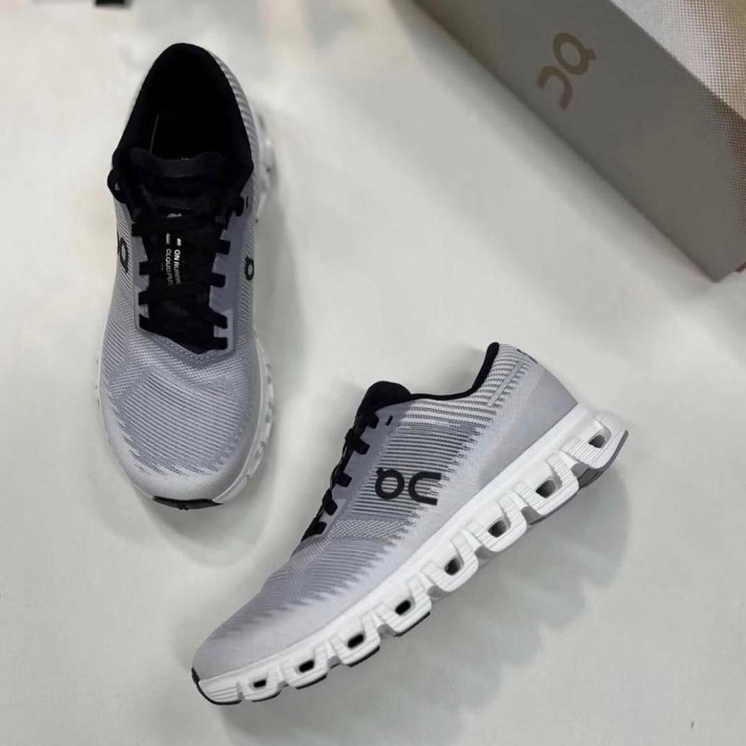 4affe07b-73a5-48fd-a993-9aeb3980d78e | AE JERSEY Pair of gray On running shoes with black laces on a white surface, showing the side and top view with a box in the background.