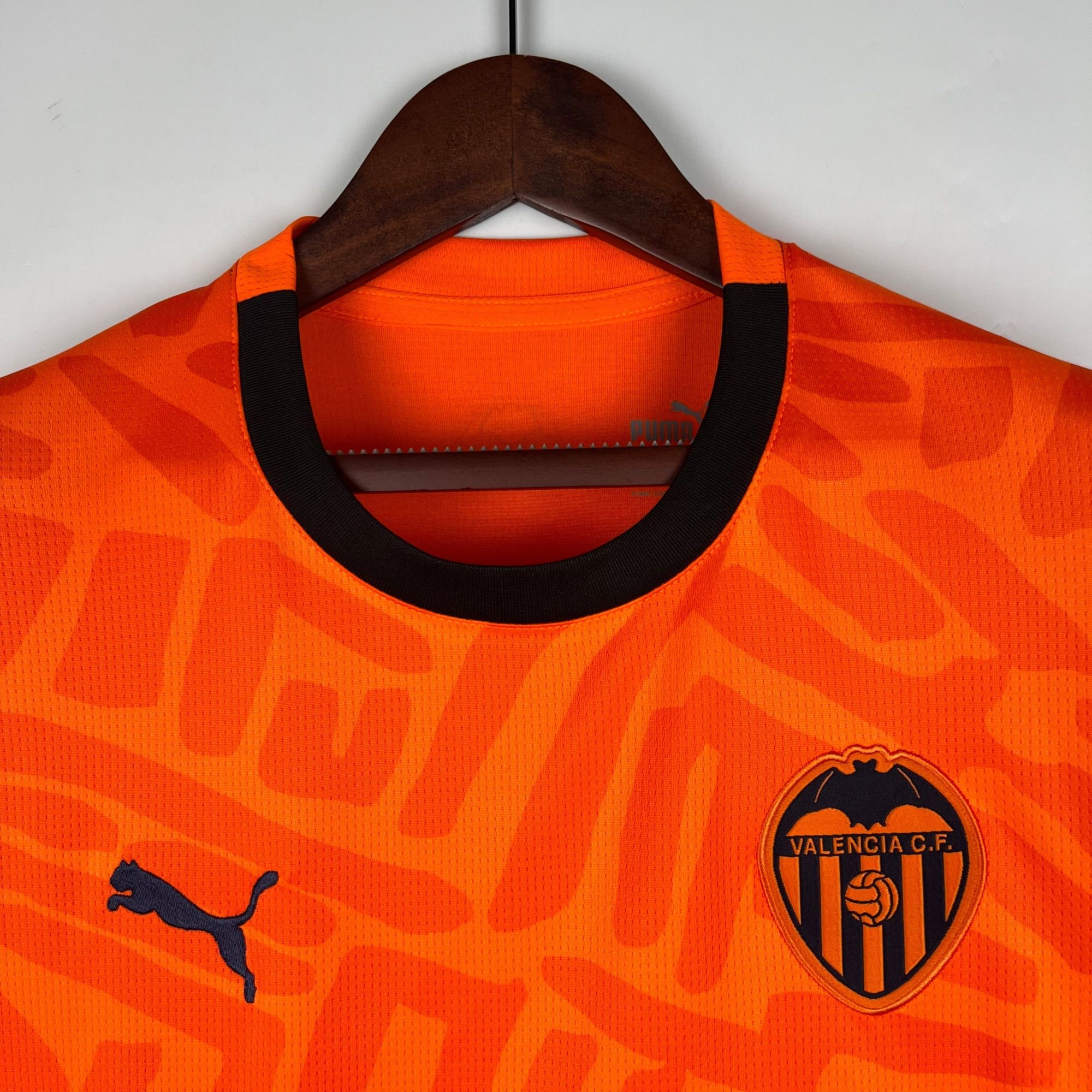 502a1c76_7ab9066d-6085-4165-b43c-6f1677b8e443 | AE JERSEY Orange Valencia CF football jersey on a hanger, showing the club crest on the chest and a black collar edge.