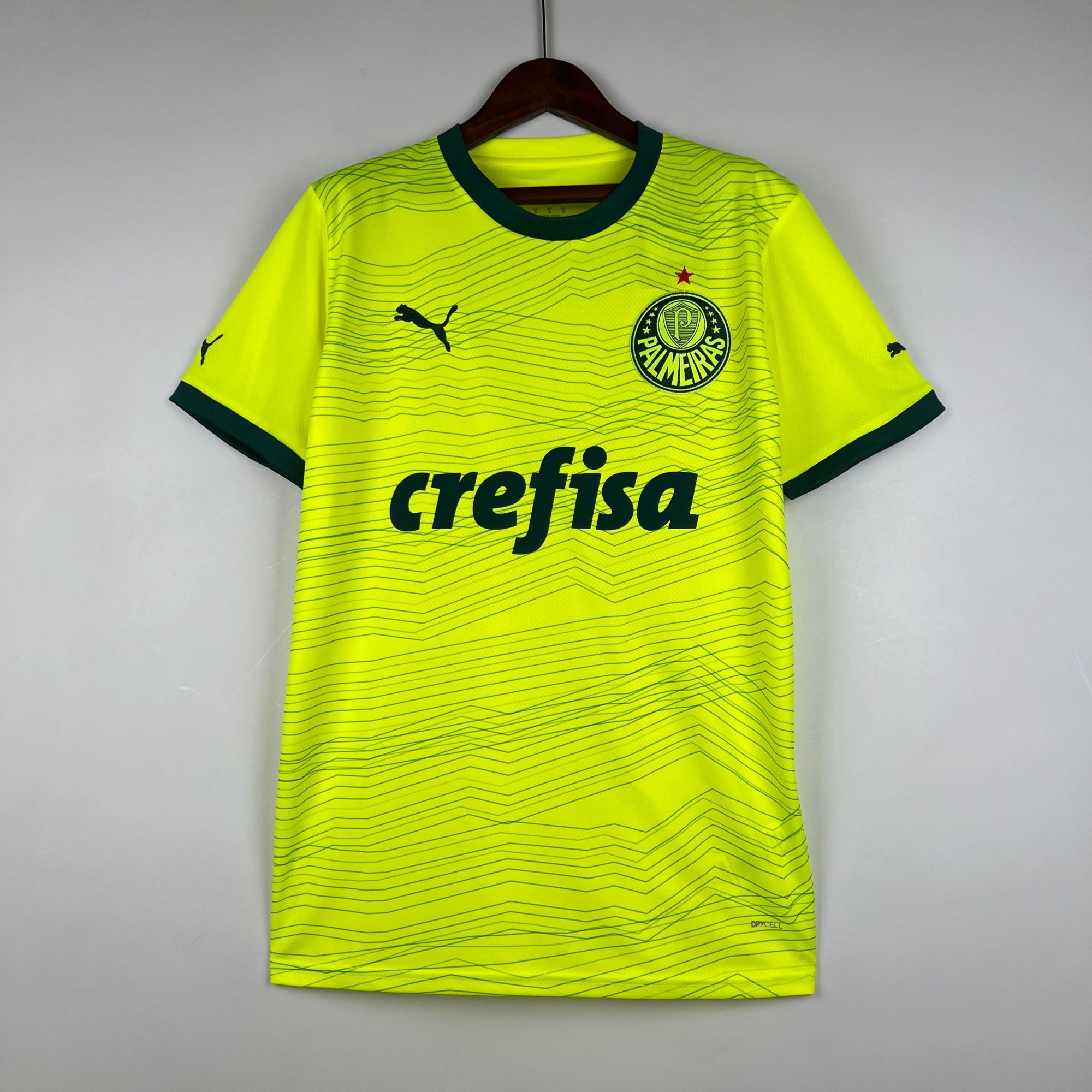 531829e9_9d5c5e45-0d3d-47a7-b28d-9091480d8eef | AE JERSEY Bright neon yellow Palmeiras soccer jersey on a hanger, showing crest and sponsor text.