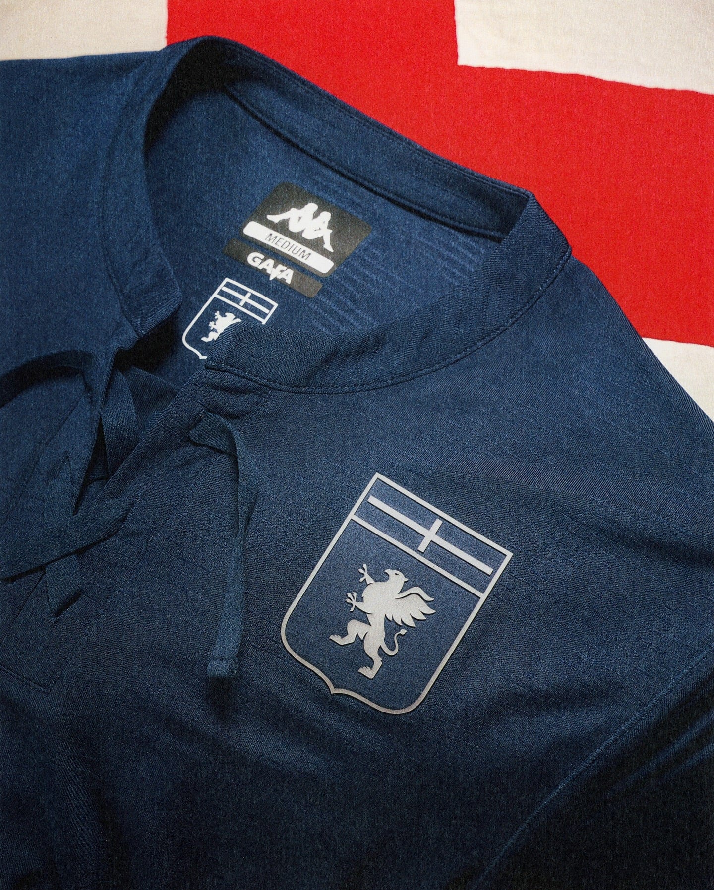 543068226_18528305548053657_2801551898754088891_n | AE JERSEY Navy polo shirt with a white lion crest inside a shield printed on the chest, GAP label and size tag reading 'Medium' visible inside the collar.