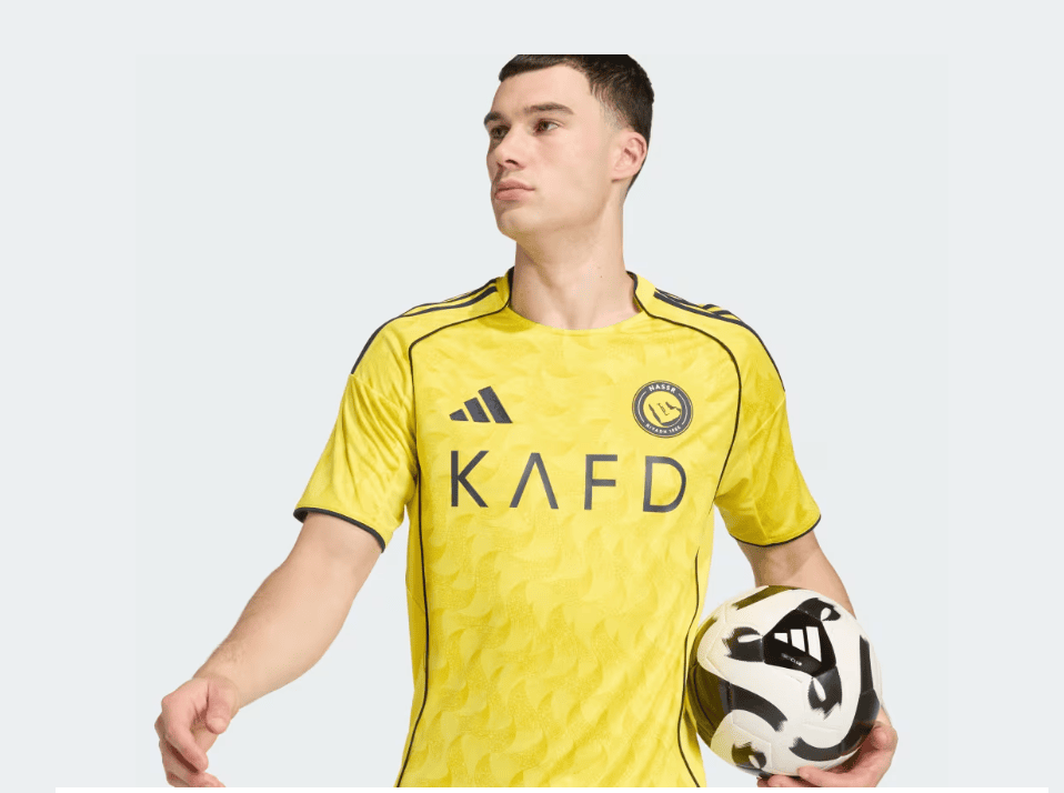 5A | AE JERSEY Soccer player in a bright yellow jersey holding a soccer ball at his side, facing left.