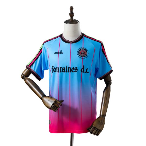 Blue to pink gradient soccer jersey with vertical pink stripes on a mannequin, featuring 'fontaines d.c.' sponsor text and club crest on the chest.