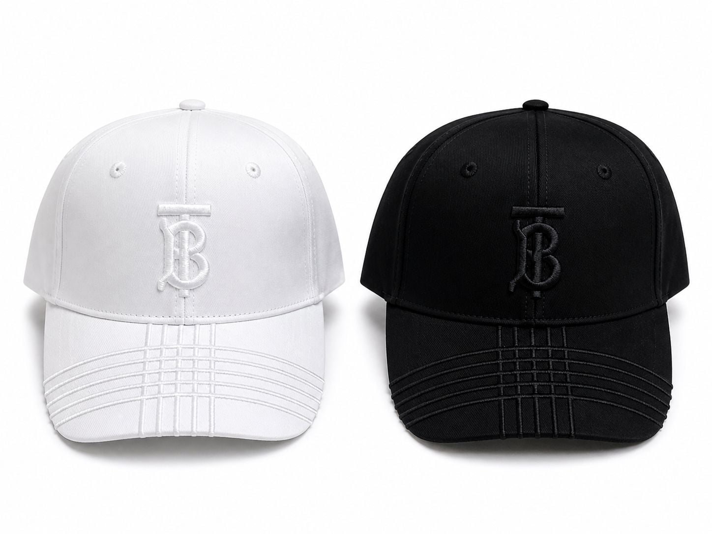 60ed3d96-bb17-4129-a5ec-240531adafd5 | AE JERSEY Two baseball caps facing forward: one white and one black, each with a stitched TB monogram on the front.