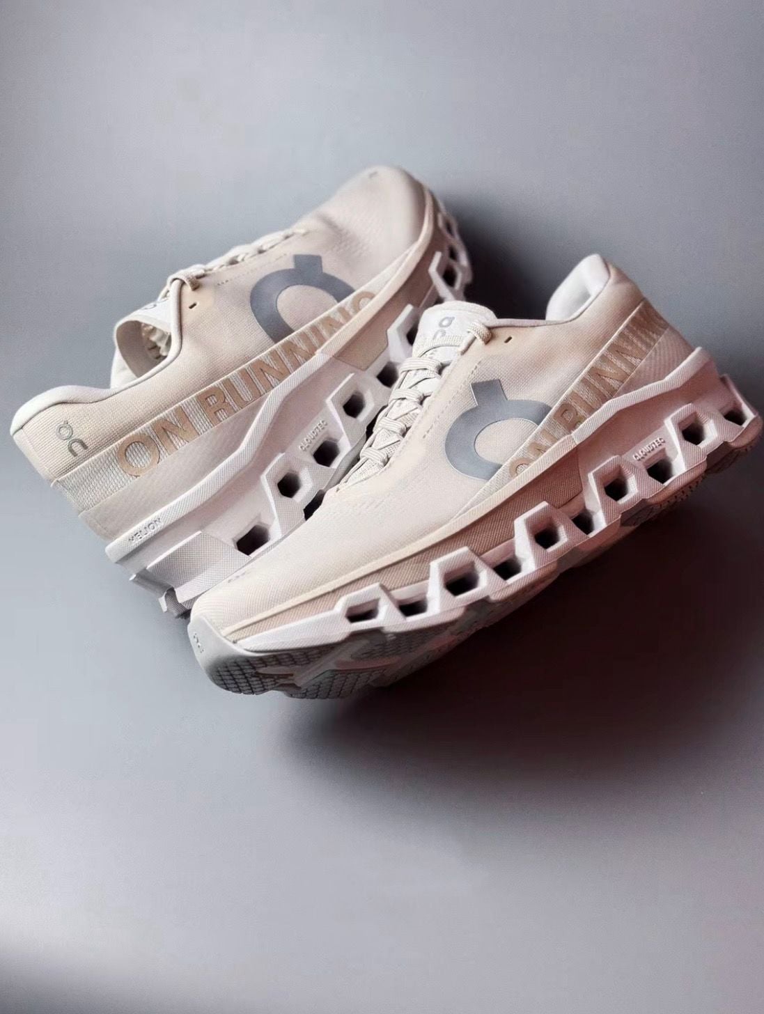 6233a0f4-a27f-478e-a686-0a9c505a5e60 | AE JERSEY Beige running shoes with a hollow block sole and a large 'ON' logo on the side, photographed as a pair.