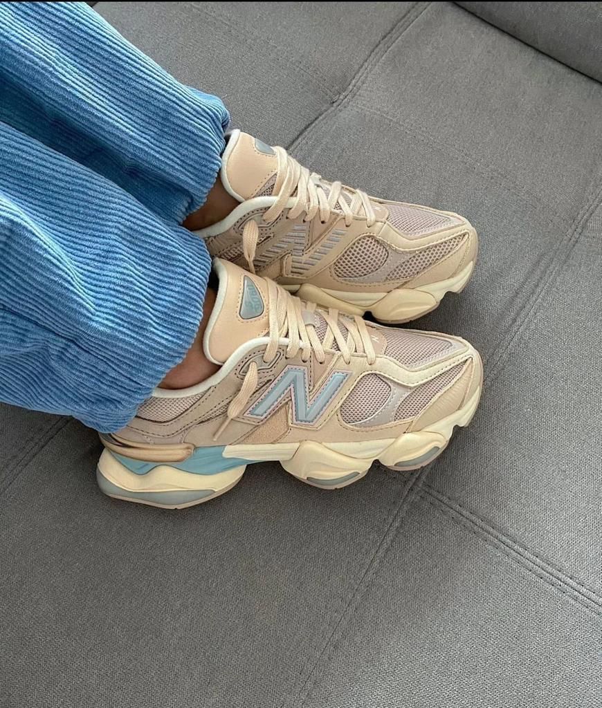68d9ff3c-e1ff-4da6-81b8-5e832059f630_732856cb-40c2-43b0-92ed-3e4f388e7826 | AE JERSEY Beige sneakers with light blue accents worn with blue corduroy pants, resting on a gray couch surface.