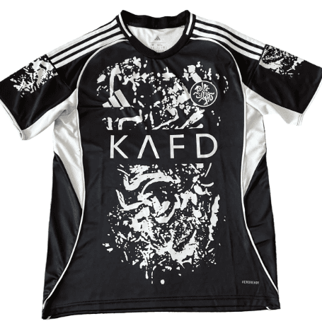 Black athletic jersey with white graphic design and shoulder stripes; large 'KAFD' text across the chest and a circular crest on the upper left.