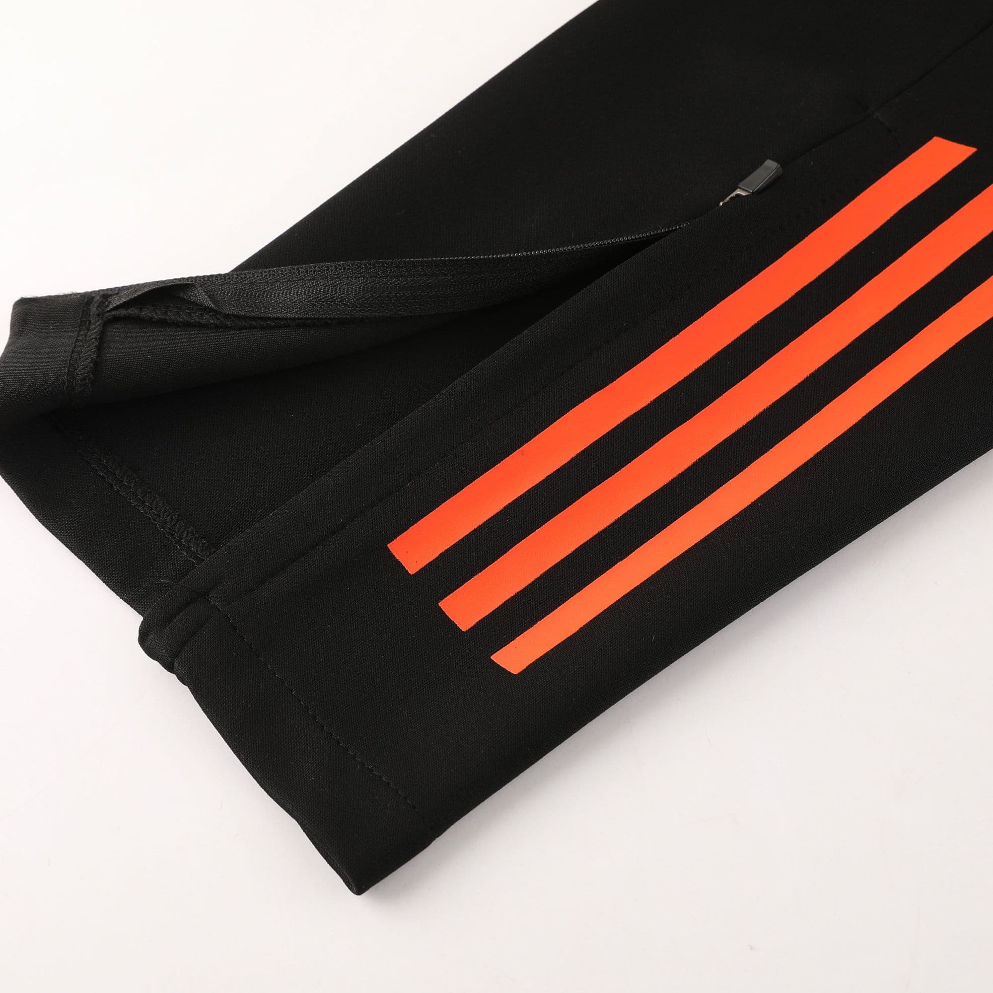 6d4fe8ec | AE JERSEY Close-up of black fabric with three bright orange diagonal stripes and a small zipper pull.