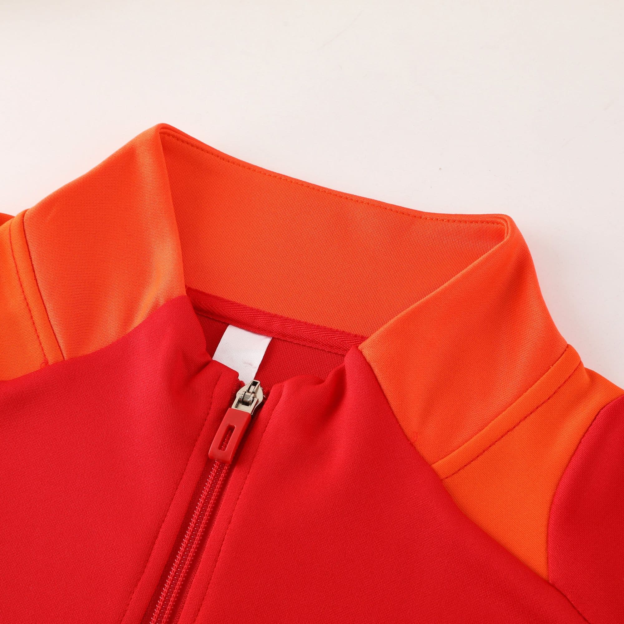7987c254 | AE JERSEY Close-up of bright orange fabric with a metal zipper and orange zipper pull.