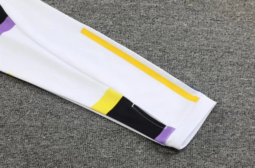 7aca7e62-ea17-4ec8-b5ed-d1341395e49f_72277113-4d64-4ab0-a379-ebdc8ab66011 | AE JERSEY White color-block sleeve with a yellow stripe and purple/black accents on a gray carpet surface.