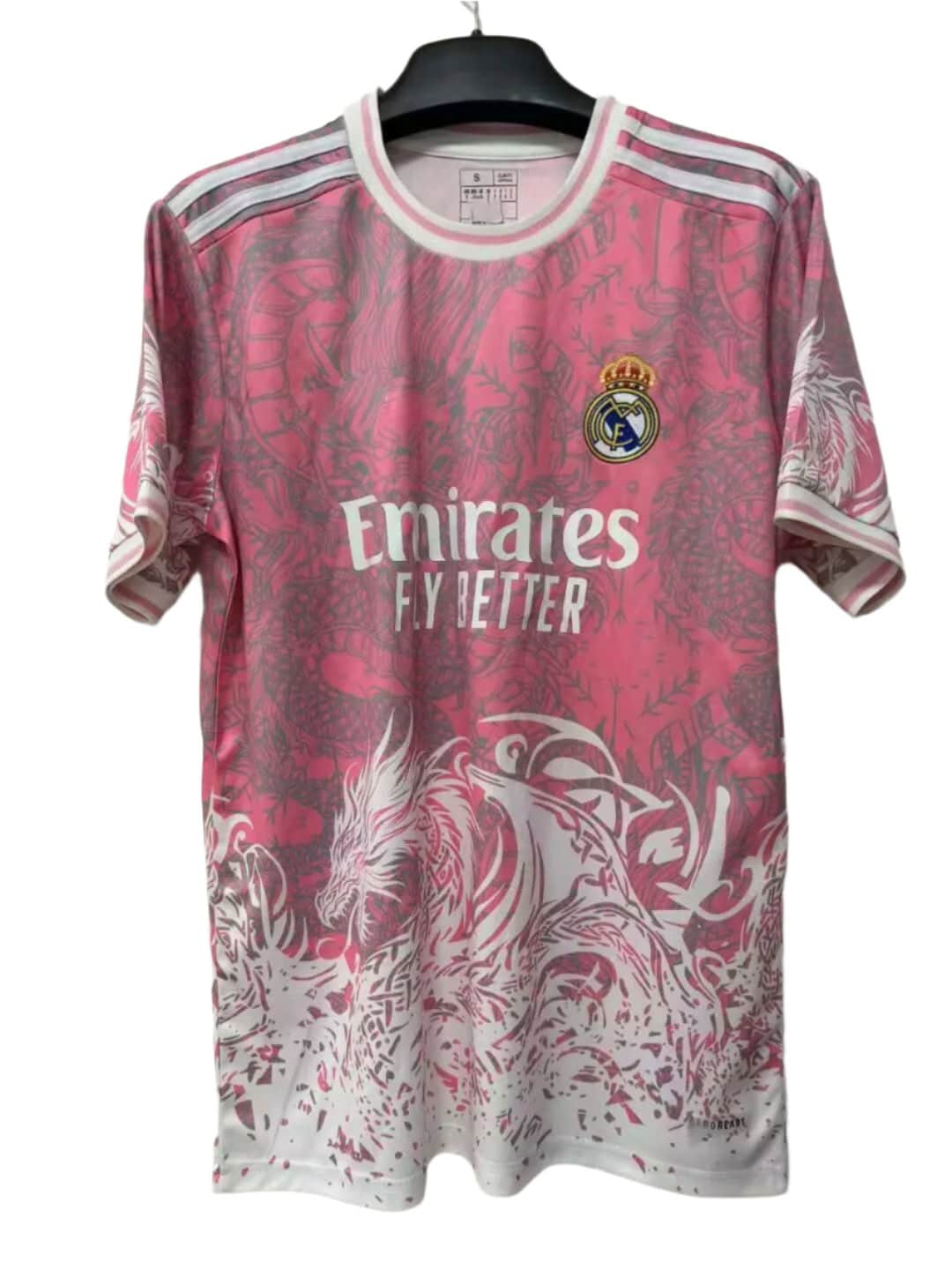 7b39ed07-f275-4dc9-835b-692934bcccd7 | AE JERSEY Pink Real Madrid football jersey on a hanger, with the Emirates Fly Better sponsor and club crest visible.