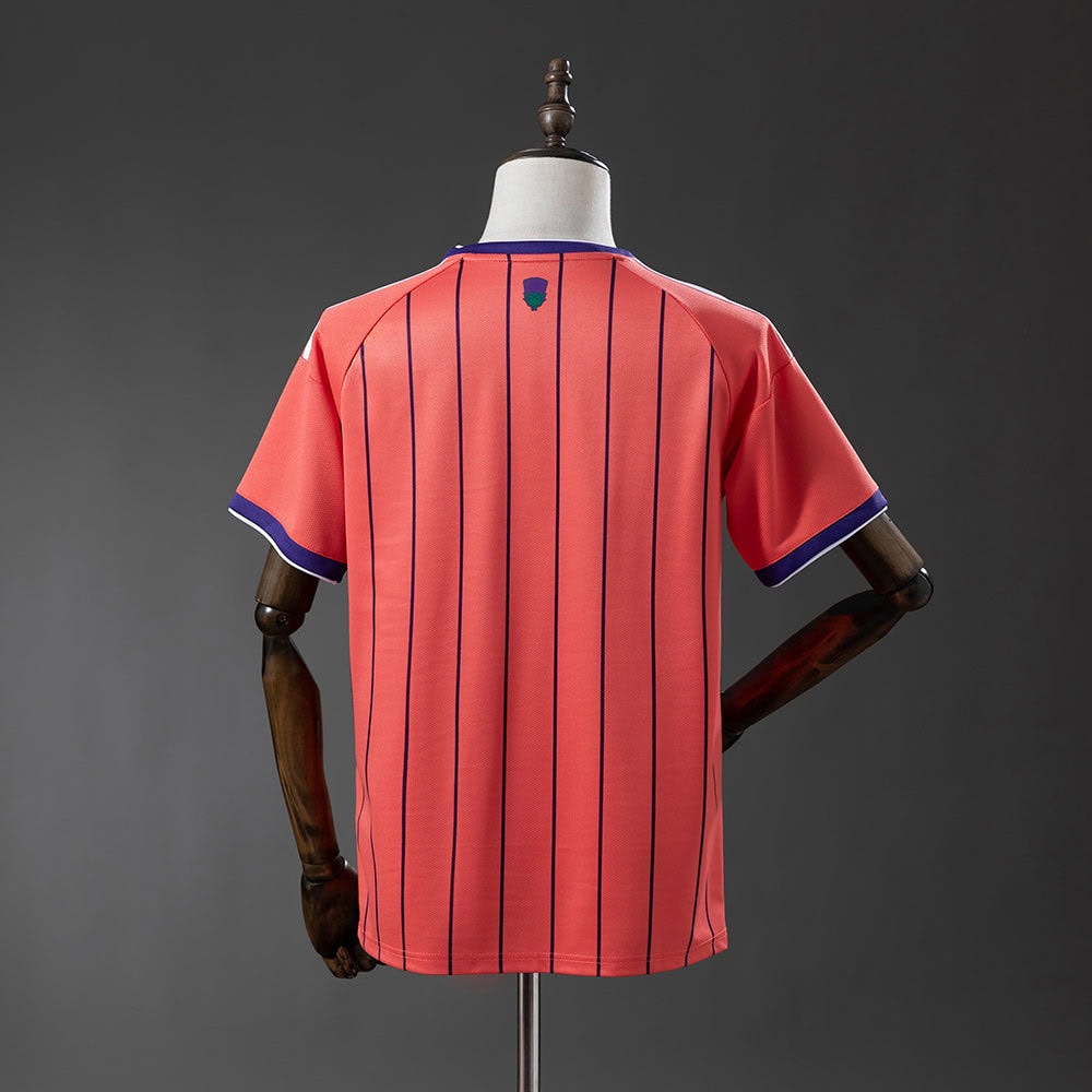 7bbbd315 | AE JERSEY Back view of a coral pink soccer jersey with vertical navy stripes and purple-trimmed sleeves on a mannequin, small crest near the neckline.