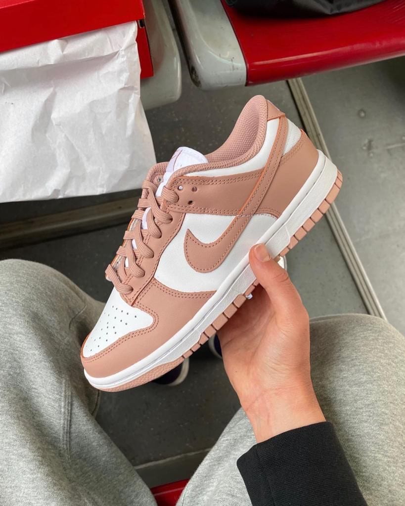 7d0d32b4-b867-4b4e-afd3-1cda03c7e189 | AE JERSEY Pink and white Nike sneaker being held in one hand, showing a blush-pink overlay and white paneling.
