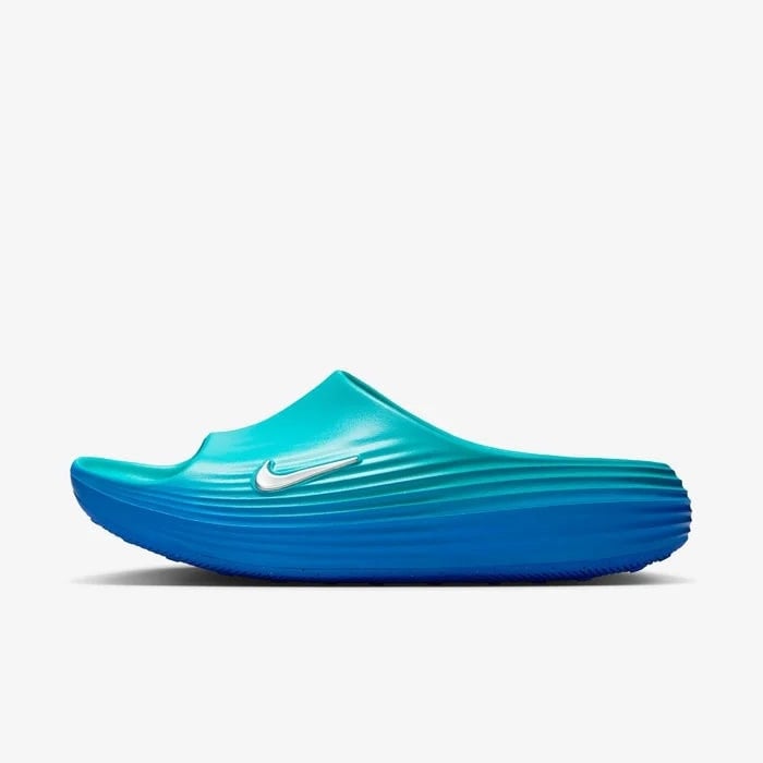 7d90fe6d_8c2f_438b_8d9e_f11cb77e6a35 | AE JERSEY Turquoise-to-navy slip-on foam shoe with a wavy ridged sole and a white Nike swoosh