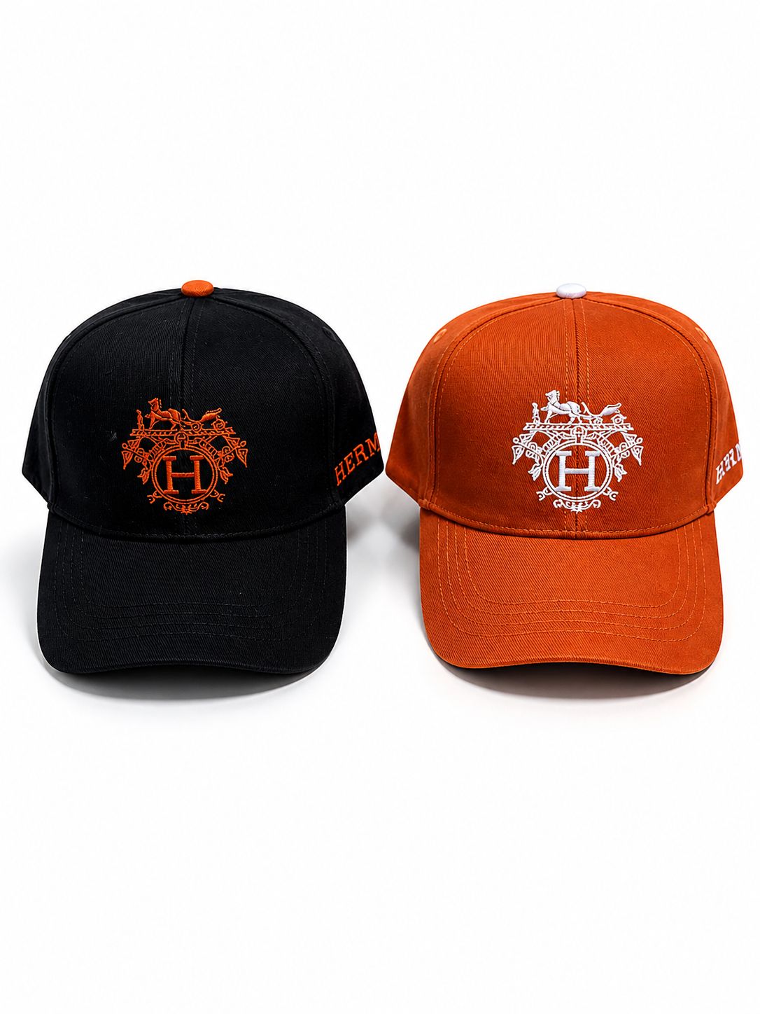 7dbf702d-6760-4c61-8a2f-2642cf021457 | AE JERSEY Two baseball caps side by side, one black and one orange, each with an ornate crest and a prominent 'H' embroidery on the front.