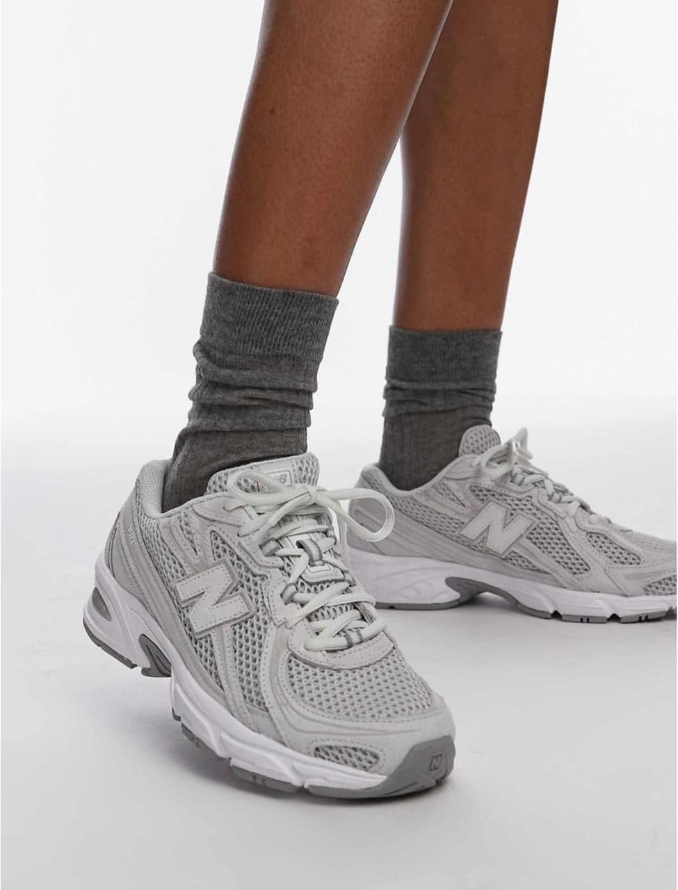 8fec9ec4-77b8-4758-ae19-9252f1b9eefe | AE JERSEY Person wearing gray crew socks and light gray athletic sneakers, standing with one foot forward.