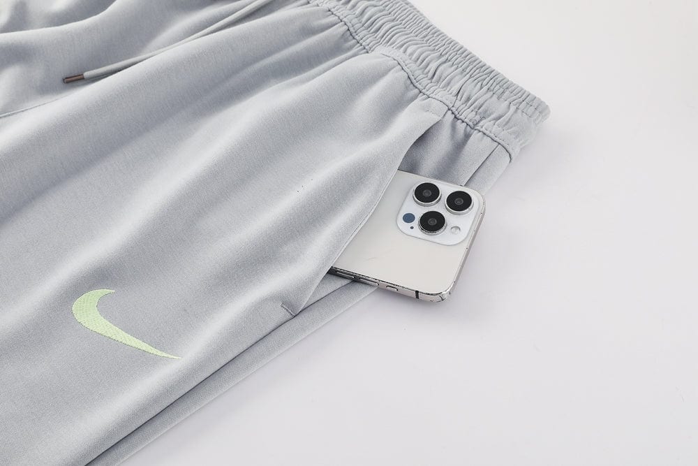 90af2ed8 | AE JERSEY Gray Nike sweatpants with a lime swoosh, showing a smartphone tucked in the pocket.