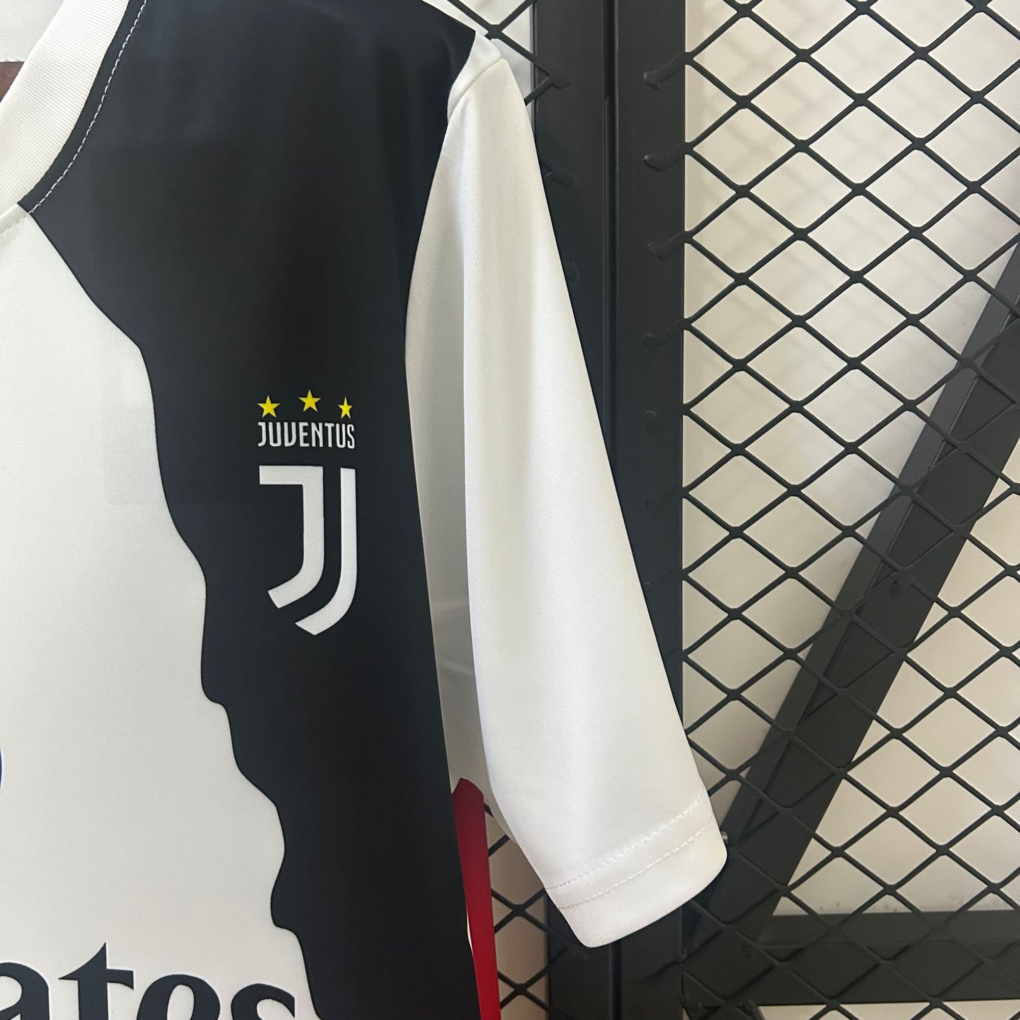 918b9458 | AE JERSEY Juventus football jersey hanging on a rack, black and white panels with three yellow stars above 'JUVENTUS' text.