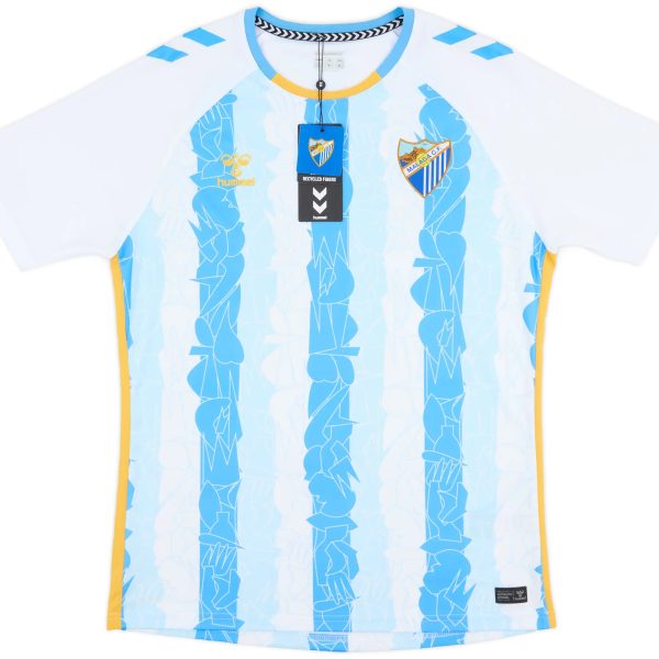Light blue football/soccer jersey with yellow trim, featuring a Malaga CF crest on the chest and Hummel logos, with product tags attached.