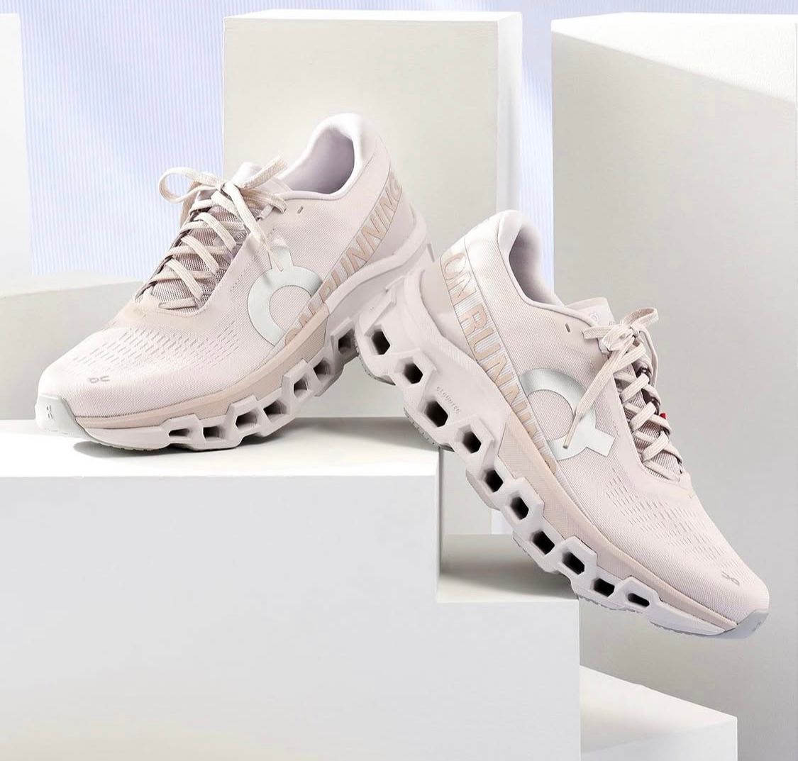 96906201-2a95-4b31-8dc2-35733bdd86ec | AE JERSEY Pair of pale pink running shoes with a distinctive hollow-hex sole, displayed on white blocks for product showcase.